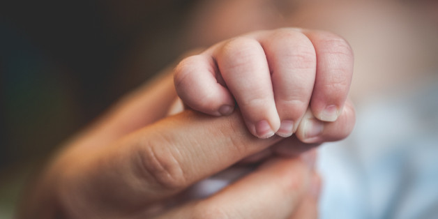 Newborn baby holding mothers hand