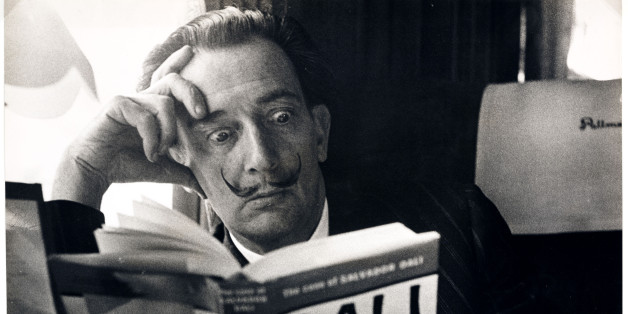 UNITED KINGDOM - NOVEMBER 21: Salvador Dali reading his biography, 6 May, 1959. A photograph of the Spanish artist Salvador Dali (1904-1989), taken by Terry Fincher for the Daily Herald newspaper. Dali is reading Fleur Cowles' book 'The Case of Salvador Dali' (1959), whilst on a train from Folkestone, having travelled from France. Cowles' book was an authorised biography of Dali. With a studied expression of shock on his face, Dali enjoys the photo opportunity. One of the most famous, charismat