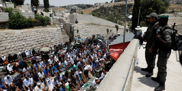 Israeli border police officers stand guard as Palestinians pray at Lions' Gate, the entrance to Jerusalem's Old City, in protest over Israel's new security measures at the compound housing al-Aqsa mosque, known to Muslims as Noble Sanctuary and to Jews as Temple Mount July 20, 2017. REUTERS/Ronen Zvulun