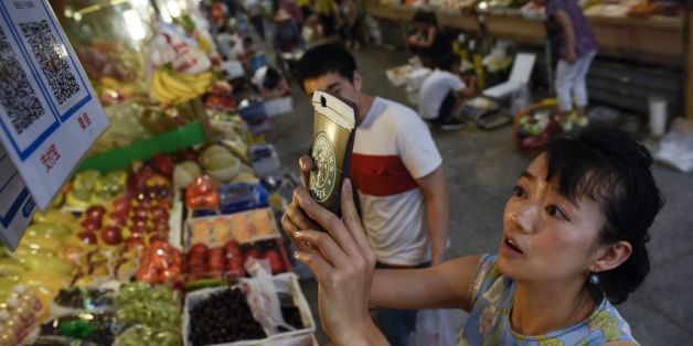 This photo taken on June 27, 2017 shows a woman making purchases by scanning QR codes using her smartphone at a fruit stall in a market in Beijing.China was the first country in the world to use paper money but centuries later the soaring popularity of mobile payment has some analysts forecasting it could be the first to stop. / AFP PHOTO / WANG ZHAO / TO GO WITH China economy internet, FOCUS by Allison JACKSON (Photo credit should read WANG ZHAO/AFP/Getty Images)