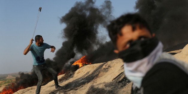 A Palestinian protester uses a sling to hurl stones towards Israeli troops during clashes near the border between Israel and central Gaza Strip July 21, 2017. REUTERS/Ibraheem Abu Mustafa TPX IMAGES OF THE DAY