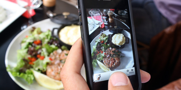 A man takes a picture with his mobile of foods in his plate as he is having lunch on July 19, 2012 in Paris. AFP PHOTO / ANA AREVALO (Photo credit should read ANA AREVALO/AFP/Getty Images)