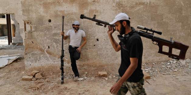 TOPSHOT - Syrian rebel fighters from the Faylaq al-Rahman brigade carry their homemade 12.7mm sniper rifle in Ain Tarma, in the eastern Ghouta area, a rebel stronghold east of the capital Damascus, on July 20, 2017. / AFP PHOTO / ABDULMONAM EASSA (Photo credit should read ABDULMONAM EASSA/AFP/Getty Images)