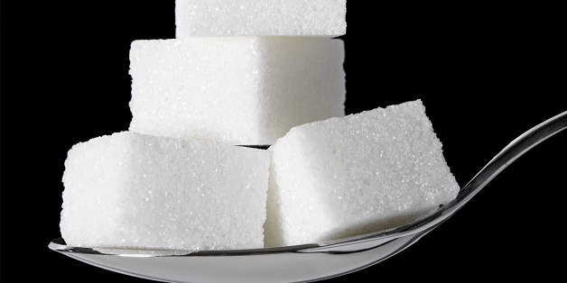 Sugar cubes stacked up on a teaspoon. Black background.