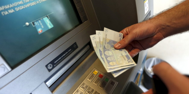 A man withdraws sixty Euros, the maximum amount allowed after the imposed capital controls in Greek banks, at a National Bank of Greece ATM in Piraeus port near Athens, Greece June 30, 2015. The head of the European Commission made a last-minute offer to try to persuade Greek Prime Minister Alexis Tsipras to accept a bailout deal he has rejected before a referendum on Sunday which EU partners say will be a choice of whether to stay in the euro. REUTERS/Yannis Behrakis