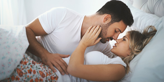 Closeup side view of late 20's couple making love in their bedroom while spending weekend in a hotel. They are just hugging and kissing at the moment