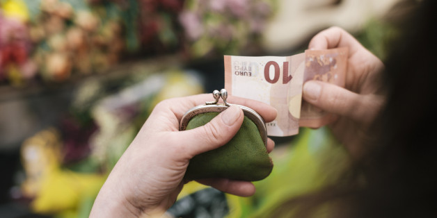 Close-up of woman paying for Flowers with a 10 Euro Bill at an outdoor Market.