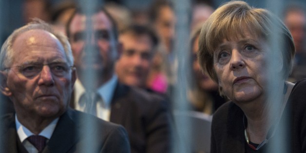 German Chancellor Angela Merkel (R) and German Finance Minister Wolfgang Schaeuble wait for the start of a concert during celebrations of the Day of the German reunification (Tag der Deutschen Einheit) in front of the Reichstag building, seat of the German lower house of Parliament (Bundestag), in Berlin on October 3, 2015. Germany's political leaders celebrate the country's 25th anniversary since the reunification of East and West Germany. AFP PHOTO / JOHN MACDOUGALL (Photo credit shoul