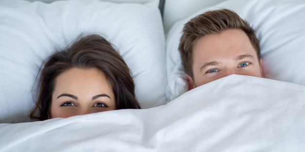 Young couple in bed covering with the sheets