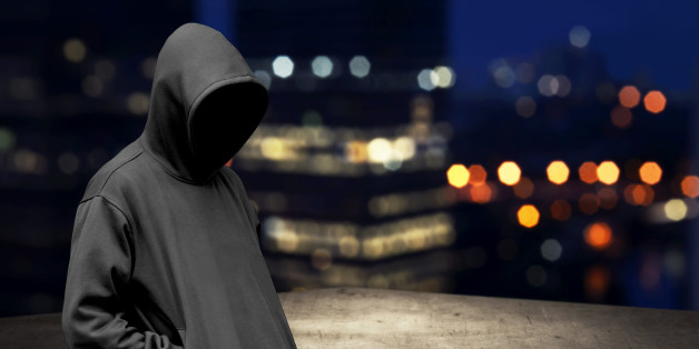 Faceless man in hood on the rooftop with city background at night time