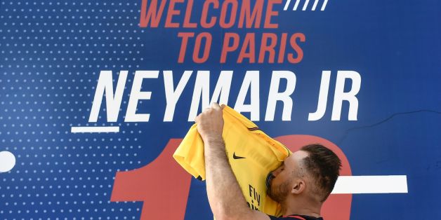 A PSG fan kisses a PSG yellow away jersey, marked with the number 10 and the name of Brazilian star Neymar, after he purchased it from the Paris-Saint-Germain (PSG) football club store on the Champs Elysees avenue in Paris on August 4, 2017.Brazilian superstar Neymar was expected in the French capital early Friday, promising to bring glory to Paris Saint-Germain after signing a world record transfer deal with the ambitious Qatari-owned club. / AFP PHOTO / PHILIPPE LOPEZ / ALTERNATIVE CROP