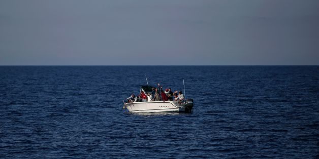 Migrants from Libya wave from a boat as they wait to be rescued by the Aquarius rescue ship run by NGO SOS Mediterranee and Medecins Sans Frontieres (MSF) in the Mediterranean Sea, 20 nautic miles from the Libyan coast, on August 2, 2017. / AFP PHOTO / Angelos Tzortzinis (Photo credit should read ANGELOS TZORTZINIS/AFP/Getty Images)