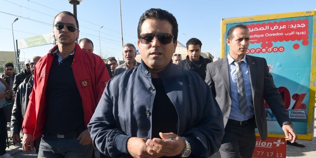 Tunisian presidential candidate and founder of the Free Patriotic Union Slim Riahi (C) arrives at a bus station during a campaign tour on November 19, 2014 in Tunis. Tunisia holds its first multi-candidate presidential election on November 23 in the final stage of a post-revolution transition that has set it apart from the turmoil of other Arab Spring states. AFP PHOTO/FETHI BELAID (Photo credit should read FETHI BELAID/AFP/Getty Images)