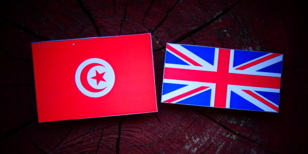 Tunisian flag with UK flag on a tree stump isolated