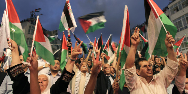 Palestinians gesture and wave flags before a public screening of Palestinian President Mahmoud Abbas' speech at the United Nations, in the West Bank city of Ramallah September 23, 2011. Abbas asked the United Nations on Friday to recognize a state for his people, even though Israel still occupies its territory and the United States has vowed to veto the move. REUTERS/Darren Whiteside (WEST BANK - Tags: POLITICS)
