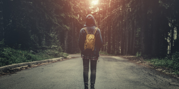 Tourist with backpack walking in a foggy forest at sunset. Stock photo.