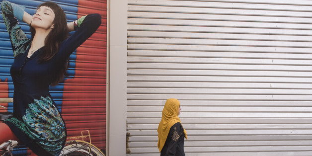 A traditionally-dressed Muslim woman walks past a poster for stylish arabic clothing in the city of Luxor, Nile Valley, Egypt. Wearing her veil and a long dress the lady observes the modesty demanded by her religion as opposed to the female on the poster, the Westernised style. (Photo by Richard Baker / In Pictures via Getty Images).