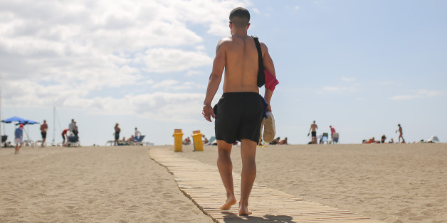 TENERIFE, SPAIN - FEBRUARY 24: A young man walks over a samall wodden path on a white sandy beach next to Los Christianos which is made from sahara sand on February 24, 2016, in Tenerife, Spain. Tenerife with his capital Santa Cruz de Tenerife and the home of Spanis highest mountain Pico del Teide (3718m) is the largest and most populous island of the seven Canary Islands. Because of its warm climate and various volcanic landscapes, Tenerife is with about five million tourists the most important, all year long holiday destination in Spain. (Photo by Christian Marquardt/Getty Images)