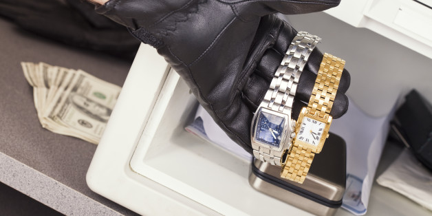 The gloved hand of a thief who is stealing watches and cash from a safe.