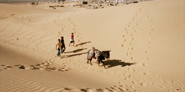 TINDOUF, ALGERIA - FEBRUARY 2: Sahrawi children carry water with a donkey through the Sahara Desert near the Sahrawi refugee camp in Dakhla on February 2, 2012 in Tindouf, Algeria. (Photo by Stefano Montesi/Corbis via Getty Images)