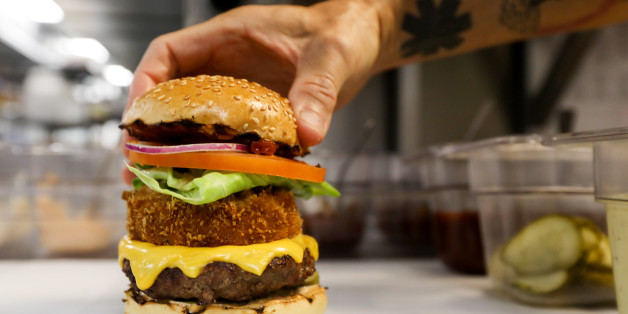 A chef with Gourmet Burger Kitchen (GBK) Ltd. delivery-only kitchen, places the top of a bun on a burger at a Deliveroo Editions field kitchen, operated by Roofoods Ltd., in Hove, U.K., on Wednesday, Aug. 9, 2017. Deliveroo, which has received $475 million in venture funding, began rolling out field kitchens to 30 locations throughout the U.K., allowing customers in new locations to order food from popular upscale restaurant chains such as MEATLiquor, Gourmet Burger Kitchen, and Busaba Eathai, the company announced in April. Photographer: Luke MacGregor/Bloomberg via Getty Images