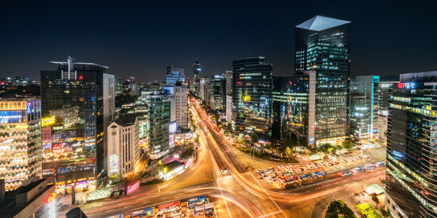 Aerial view of famous crowded Crossing at Downtown Gangnam Station at night with traffic and surrounding tall skyscrapers. New Voigtlander Helinar 10mm Ultra Wide Angle, Unique Perspective, 42MP shot from aerial perspective. Gangnam District, Seoul, South Korea