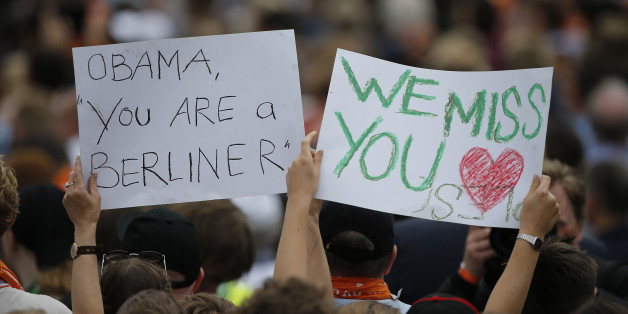 People hold posters as they attend a discussion by German Chancellor Angela Merkel and former U.S. President Barack Obama at the German Protestant Kirchentag in front of the Brandenburg Gate in Berlin, Germany, May 25, 2017. REUTERS/Axel Schmidt