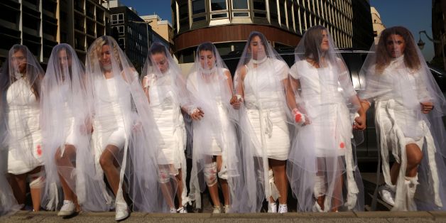 Activists from the Lebanese NGO Abaad (Dimensions), a resource centre for gender equality, dressed as brides and wearing injury patches hold a protest in downtown Beirut on December 6, 2016, against article 522 in the Lebanese penal code.
The article shields rapists from prosecution on the condition that they marry their victim, a phenomenon that is still practised in the country, especially among conservative families whose chief aim is to preserve the family's so-called 'honour.' / AFP / PATRICK BAZ (Photo credit should read PATRICK BAZ/AFP/Getty Images)