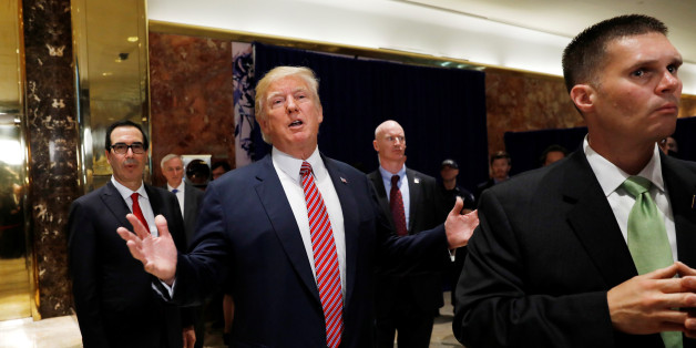 U.S. President Donald Trump stops to respond to more questions about his responses to the violence, injuries and deaths at the "Unite the Right" rally in Charlottesville as he walks away flanked by Treasury Secretary Steven Mnuchin (L) and U.S. Secret Service agents (R) after speaking to the media in the lobby of Trump Tower in Manhattan, New York, U.S., August 15, 2017. REUTERS/Kevin Lamarque