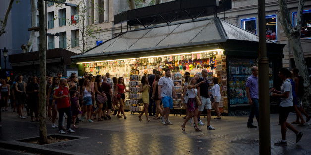 People walk past a kiosk in Las Ramblas of Barcelona, Spain, on 18 August 2017, a day after a van ploughed into the crowd, killing 14 persons and injuring over 100. (Photo by Jordi Boixareu/NurPhoto via Getty Images)