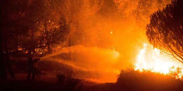 Firefighters work to put out a wildfire on a fire in Carnoux-en-Provence, southeastern France, on August 19, 2017. Vacationers who were staying near Aubagne were momentarily evacuated on the night of August 19 and residents confined to their homes as a wildfire burned through 200 hectares of vegetation, the Bouches-du-Rhone prefecture said. / AFP PHOTO / BERTRAND LANGLOIS (Photo credit should read BERTRAND LANGLOIS/AFP/Getty Images)