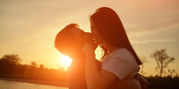 Romantic sillhouette couple love at sunset. Two young people kissing near lake. Emotions and romance concept