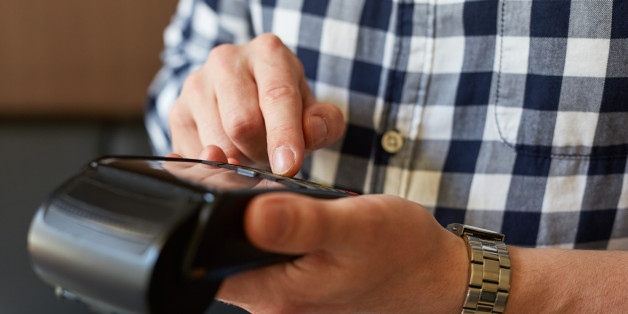 Male hand entering PIN number using payment terminal