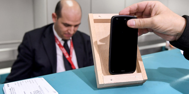 A Tunisian traveller measures the size of his cell phone in a frame on the check-in counter to be cleared for boarding his London-bound flight at Tunis-Carthage International Airport, on March 25, 2017.
The United States this week announced a ban on all electronics larger than a standard smartphone on board direct flights out of eight countries across the Middle East, in effect from March 25, 2017. US officials would not specify how long the ban will last, but Emirates told AFP that it had been instructed to enforce the measures until at least October 14. Britain has also announced a parallel electronics ban targeting all flights out of Egypt, Turkey, Jordan, Saudi Arabia, Tunisia and Lebanon. / AFP PHOTO / FETHI BELAID (Photo credit should read FETHI BELAID/AFP/Getty Images)
