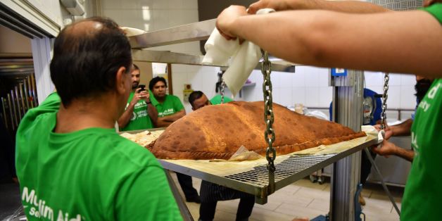 Muslim Aid staff and volunteers work as they attempt to construct and cook the world's largest samosa at the East London Mosque in London on August 22, 2017.The record breaking samosa was prepared, cooked and served up by the international relief and development agency Muslim Aid at the East London Mosque. The samosa will go to feed the homeless in the neighbourhood as part of the traditional good deeds associated with the Muslim festival of Eid al-Adha. The samosa weighed 153 kilos and was cert