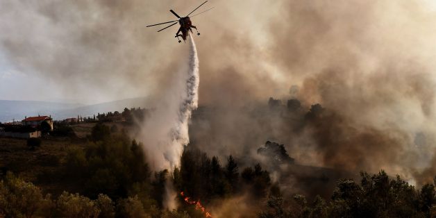 TOPSHOT - A firefighting helicopter drops water on a fire burning east of the Greek capital Athens on August 15, 2017.
The army was called in to assist firefighters around Kalamos, 45 kilometres (30 miles) east of Athens, where a fire has been burning since August 13. In all, 146 fires have broken out across Greece since then according to authorities.
/ AFP PHOTO / ARIS MESSINIS (Photo credit should read ARIS MESSINIS/AFP/Getty Images)