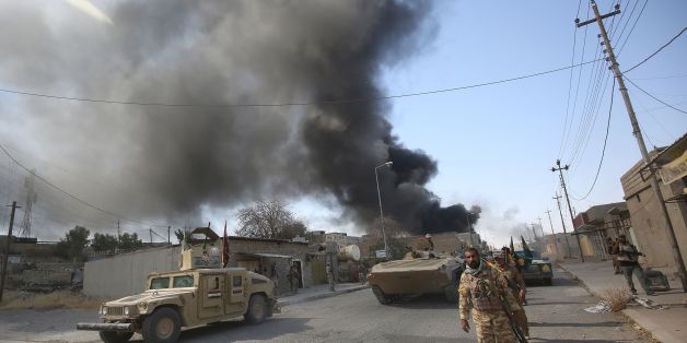 Smoke billows in the background as members of the Iraqi forces, backed by the Hashed Al-Shaabi (Popular Mobilization units), advance through a street in the town of Tal Afar, west of Mosul, after the Iraqi government announced the launch of the operation to retake it from Islamic State (IS) group control, on August 26, 2017. / AFP PHOTO / AHMAD AL-RUBAYE (Photo credit should read AHMAD AL-RUBAYE/AFP/Getty Images)