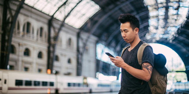 Chinese man standing on a train station and using phone
