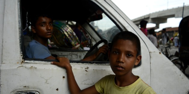 From left, Christy (14), Rony (10) look at the camera during a traffic signal on Thursday , July, 20 2017 in Dhaka, Bangladesh. Christy has been working as a driver for a year and Rony working around two weeks as a helperand want to be a driver soon, Rony said. According to the labour law in Bangladesh the minimum age for employment is 14 years. The enforcement of such labour law is virtually impossible in Bangladesh because most of child labourer are employed in the internal sector such as smal