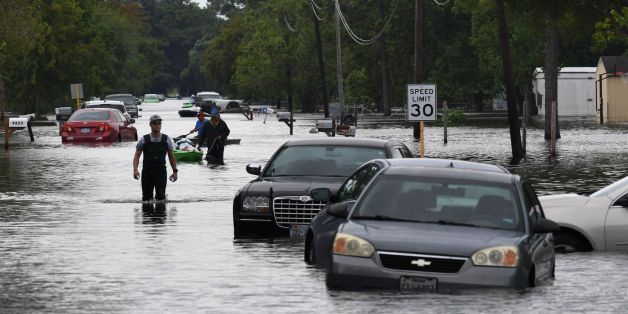 TOPSHOT - Local residents wade through flooded streets after Hurricane Harvey caused heavy flooding in Crosby, Texas on August 30, 2017.
Monster storm Harvey made landfall again Wednesday in Louisiana, evoking painful memories of Hurricane Katrina's deadly strike 12 years ago, as time was running out in Texas to find survivors in the raging floodwaters. / AFP PHOTO / MARK RALSTON (Photo credit should read MARK RALSTON/AFP/Getty Images)
