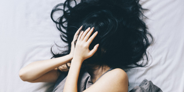 Young woman covering her face with hair and hands.