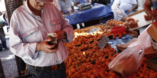 A customer counts euro banknotes at a fresh fruit street vendor's stall in the suburb in Athens, Greece, on Wednesday, June 14, 2017. Prime minister Alexis Tsipras has spent nearly two years telling Greeks that a debt deal and inclusion in the European Central Banks quantitative-easing program will unleash an investment boom that salves the pain of austerity. Photographer: Kostas Tsironis/Bloomberg via Getty Images
