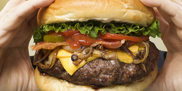 man about to take a bite of a large hamburger
