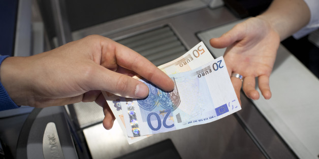 BONN, GERMANY - JULY 04: A shopper paying in cash at the supermarket check-out pictured on July 04, 2013 in Bonn, Germany. (Photo by Ute Gabrowsky/Photothek via Getty Images)