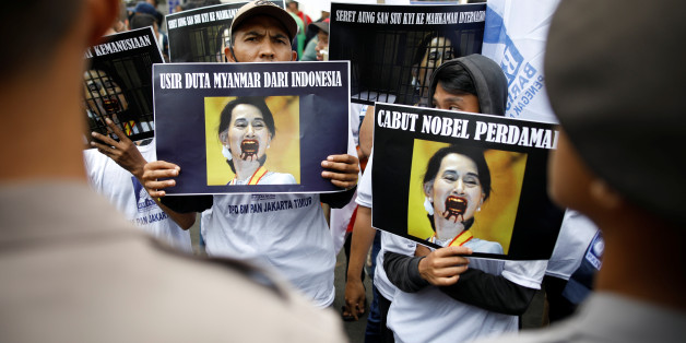 Police officers watch as protesters hold signs against the Myanmar government and its State Counsellor Aung San Suu Kyi, during a rally in support of Myanmar's Rohingya Muslim minority, outside of the Myanmar embassy in Jakarta, Indonesia September 4, 2017. Picture taken September 4, 2017. REUTERS/Darren Whiteside