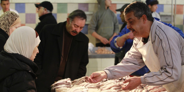 A vendor (R) sells fish to customers at a central market in Tunis February 2, 2011. Only 7 percent of Tunisia's population lives in poverty, the World Bank says, one of the lowest levels in the region and population growth is slower than in other countries in North Africa and the Middle East thanks to family planning support. REUTERS/Zoubeir Souissi (TUNISIA - Tags: FOOD SOCIETY)