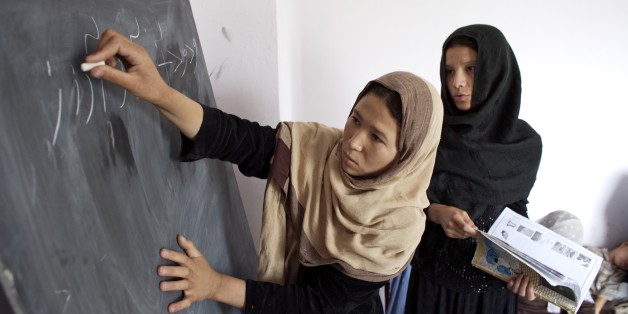 An Afghan woman writes Dari letters on blackboard with the help of the teacher, during an adult literacy class for women, at Dust-e-Noor neighborhood, in Mazar-e-Sharif, in the northern province of Balkh. Dari is the Afghan dialect of the Persian or Farsi language. A total of 50 women attend the literacy centre, one of 7,000 such centers in the province. Nationwide, 48,000 women participate in the literacy program. Afghanistan. June 28, 2007. (Photo by: Majority World/UIG via Getty Images)
