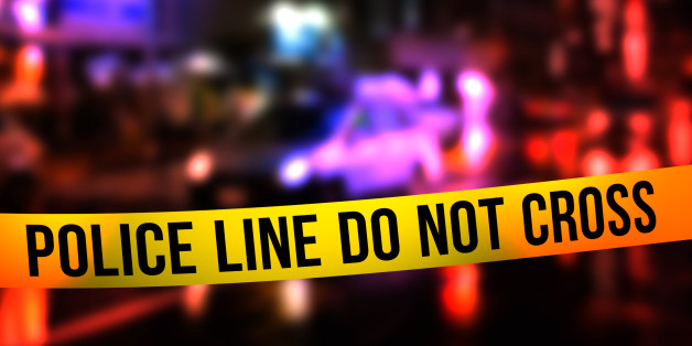 A night time street scene with focus on a 'Police Line Do Not Cross' tape across.