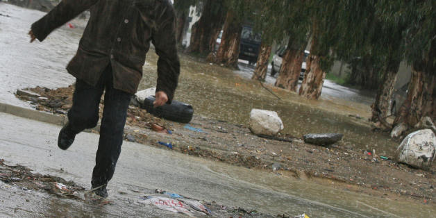 An Algerian man runs under a heavy rain in a street of Astawali, a western suburb of Algiers City 27 November 2007. A bridge collapsed due to heavy rains and floods in Algiers capital since three days. Four people died and a dozen of roads were cut. AFP PHOTO/FAYEZ NURELDINE (Photo credit should read FAYEZ NURELDINE/AFP/Getty Images)