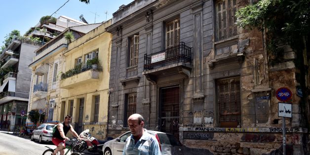 People pass a neoclassical building for sale in one of the oldest districts of Athens on July 7, 2017.
A 1983 law for the conservation and development of neoclassical buildings obliged the property owners to restore them, but the 2010 crisis, the over-taxation of real estate and the absence of loans or State aid has led lead to their abandonment. 'Currently, with the crisis, it is expensive and difficult to repair this kind of buildings, there are no more state aids, people prefer to abandon or demolish them,' says architect Maria Daniil , specialized in the buildings of the end of the nineteenth and twentieth centuries.Famous for its ancient sites, Athens also has a neoclassical architectural heritage of the nineteenth and twentieth centuries, of which the few remaining buildings are threatened with disappearing for lack of a policy in favor of their conservation. / AFP PHOTO / LOUISA GOULIAMAKI (Photo credit should read LOUISA GOULIAMAKI/AFP/Getty Images)
